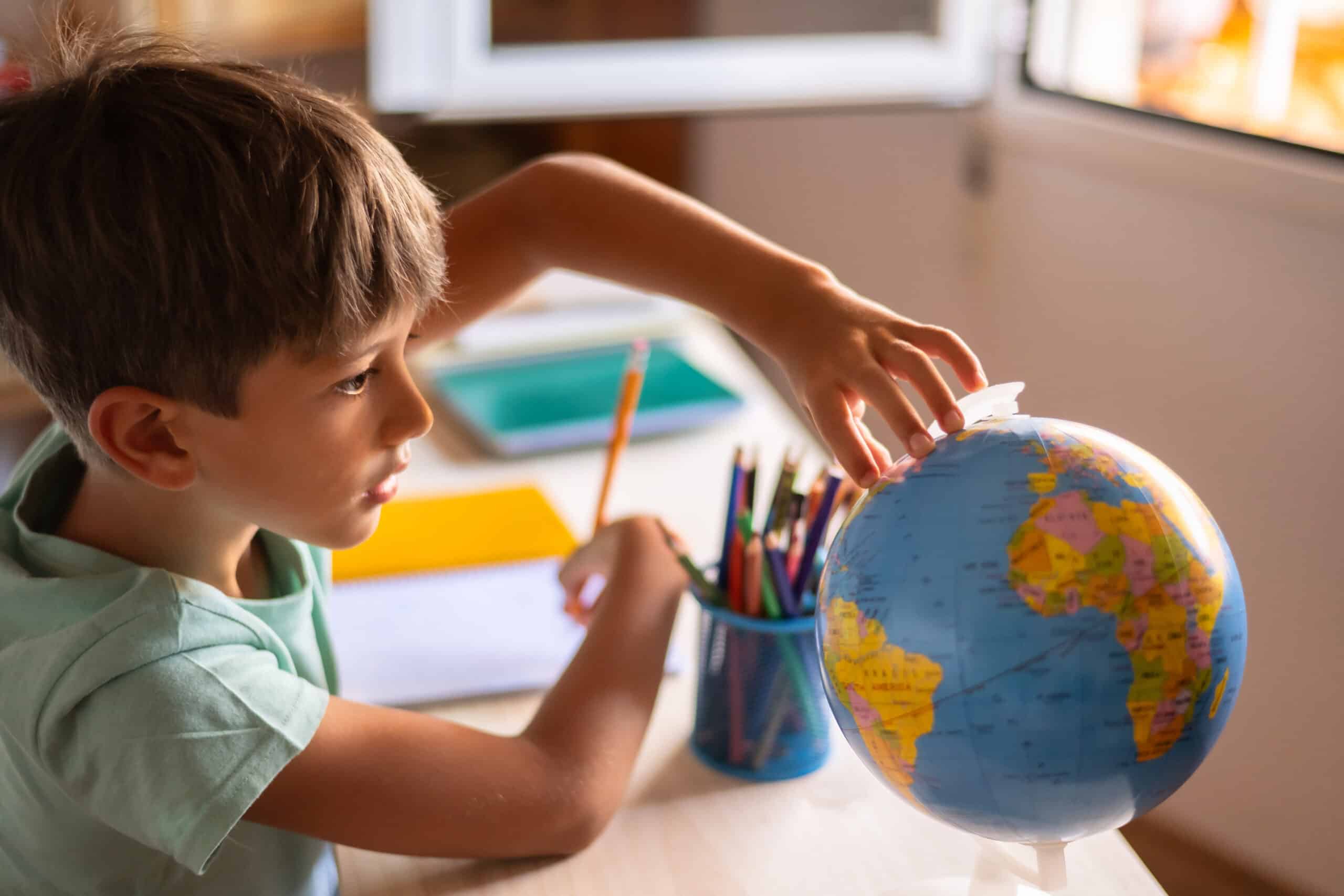 Ecolier qui tourne un globe à l'école